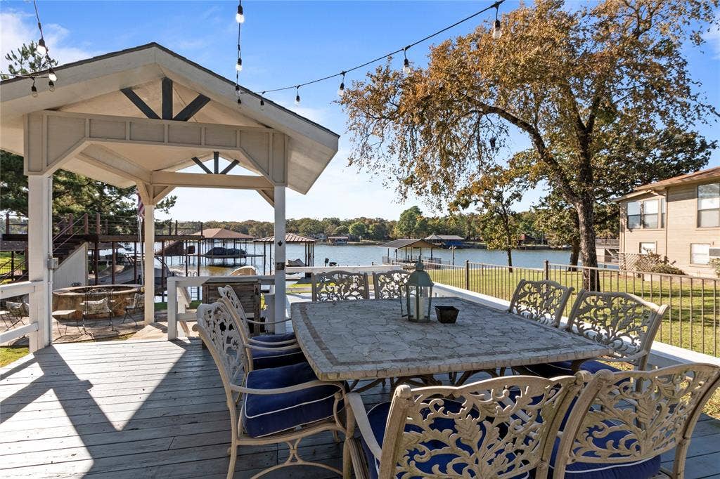 230 Bushwhacker Drive, Mabank, TX 75156 Covered outdoor deck featuring a gabled pavilion, overhead string lighting, metal railing, and direct water access