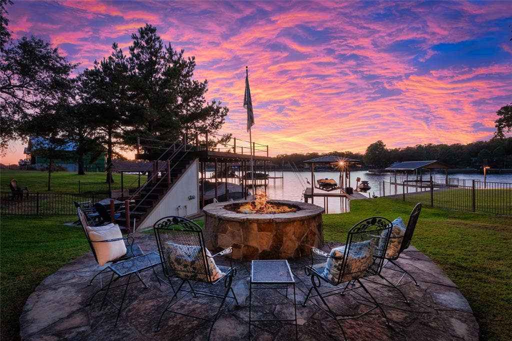 230 Bushwhacker Drive, Mabank, TX 75156 Flagstone patio featuring a circular stone fire pit, metal perimeter fencing, and a multi-level dock structure