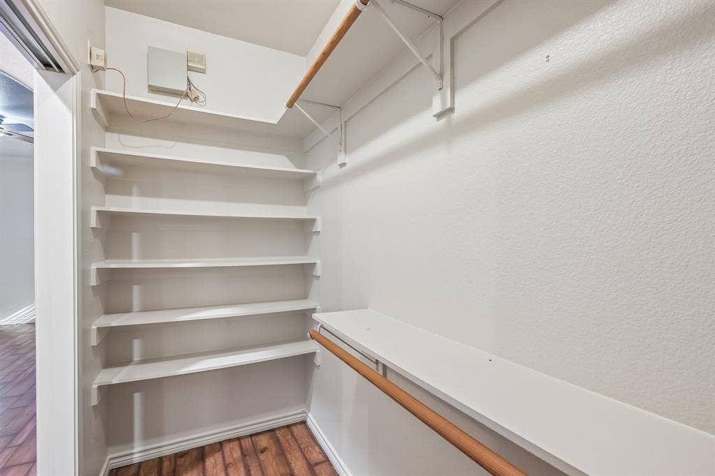 Built-in shelving, hanging rods, wood-finish flooring, and white painted walls