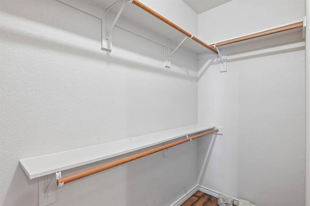 Walk-in closet featuring white shelving and wood-finish hanging rods
