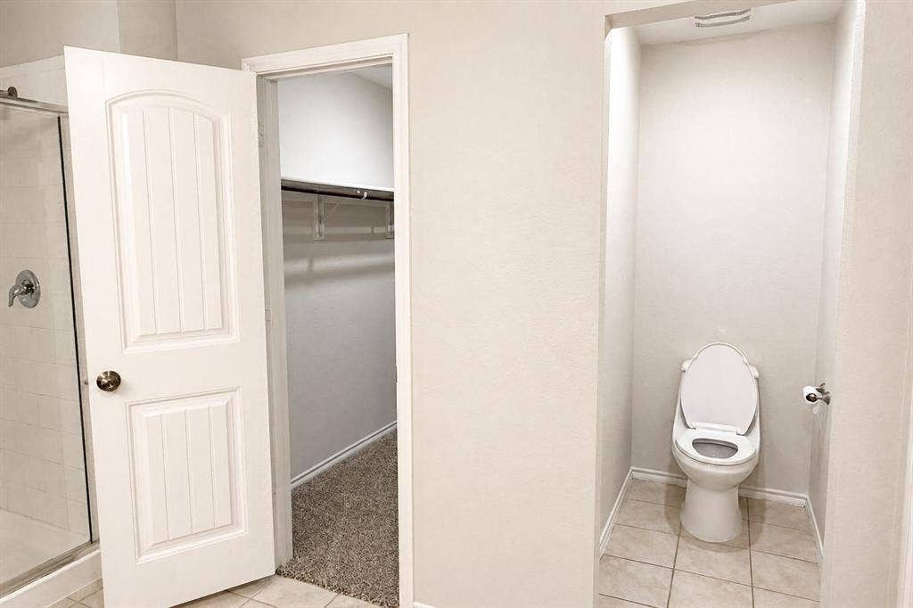 Walk-in closet featuring wire shelving and textile flooring, paired with a dedicated water closet and a glass-enclosed shower featuring a metallic fixture
