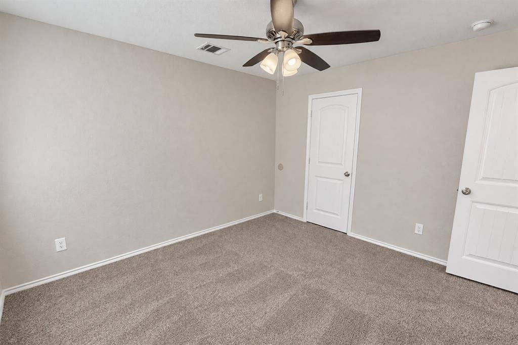 Neutral wall tones, carpeted flooring, multi-panel doors with chrome hardware, and a ceiling fan with integrated lighting