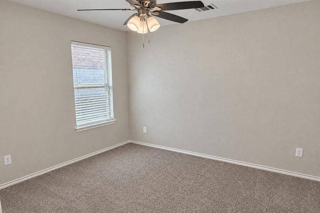 Neutral-toned interior space featuring wall-to-wall carpeting, a multi-blade ceiling fan with integrated tri-light fixture, and a single-pane window with horizontal blinds