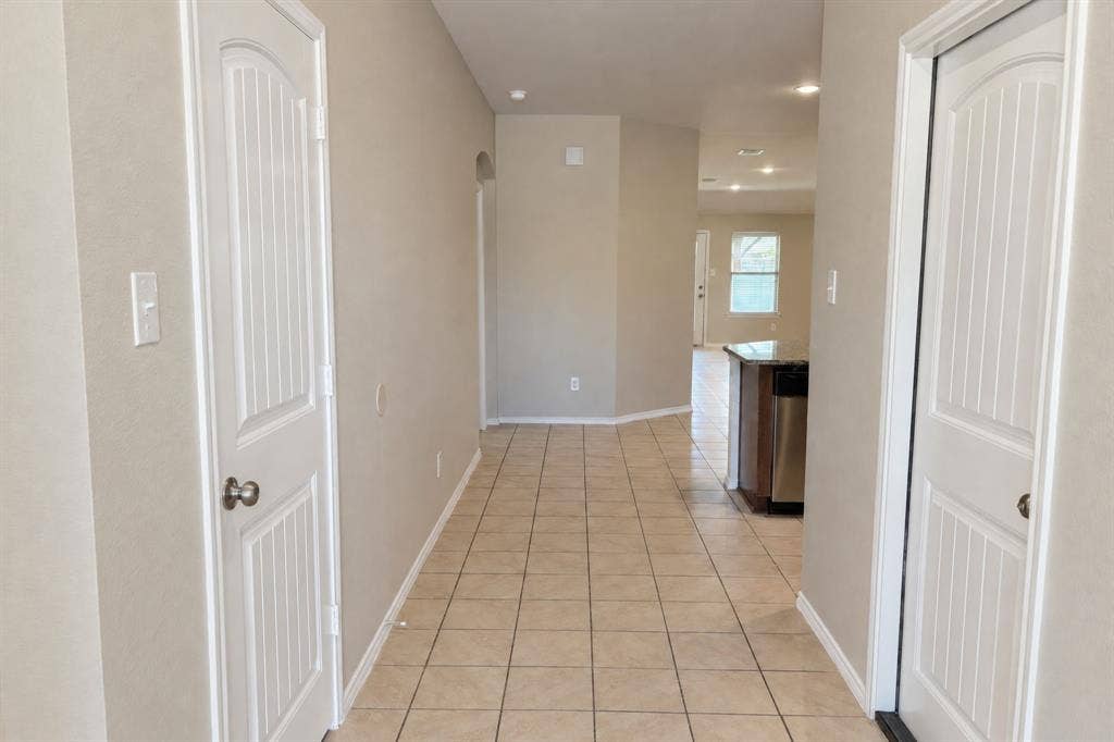 Neutral-toned interior hall featuring tile flooring and two-panel arched interior doors