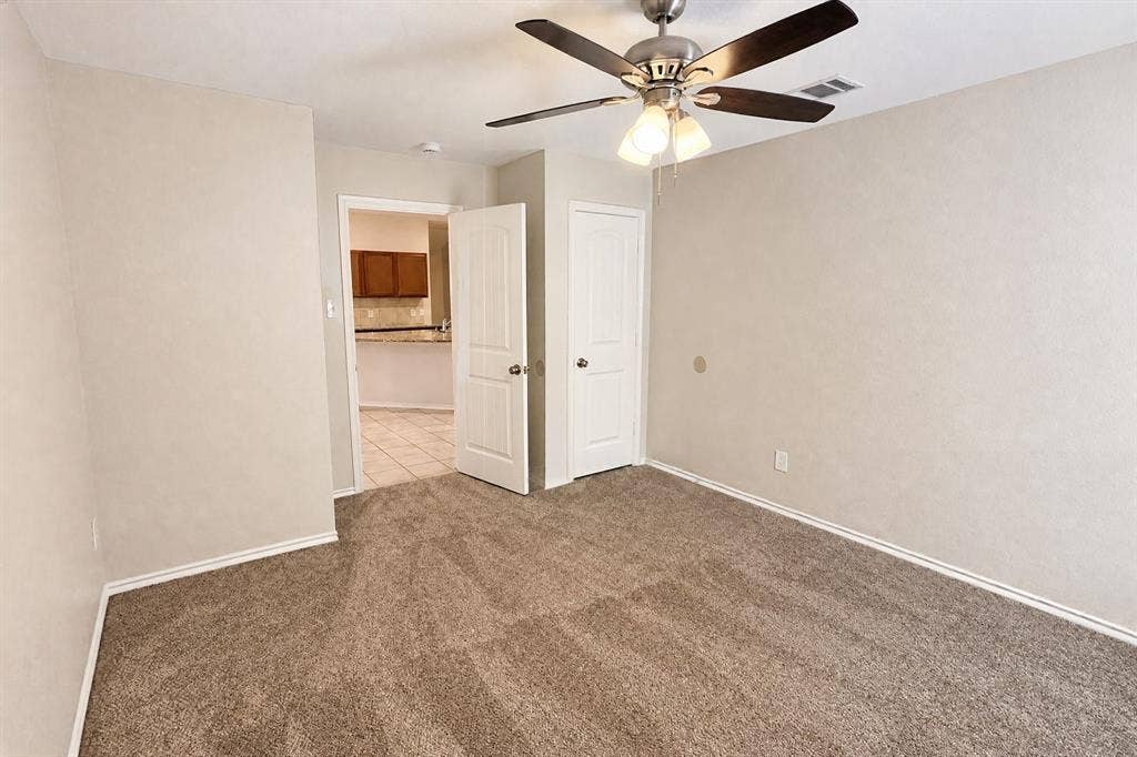 Neutral-toned carpeting, ceiling fan with integrated light fixture, and paneled doors