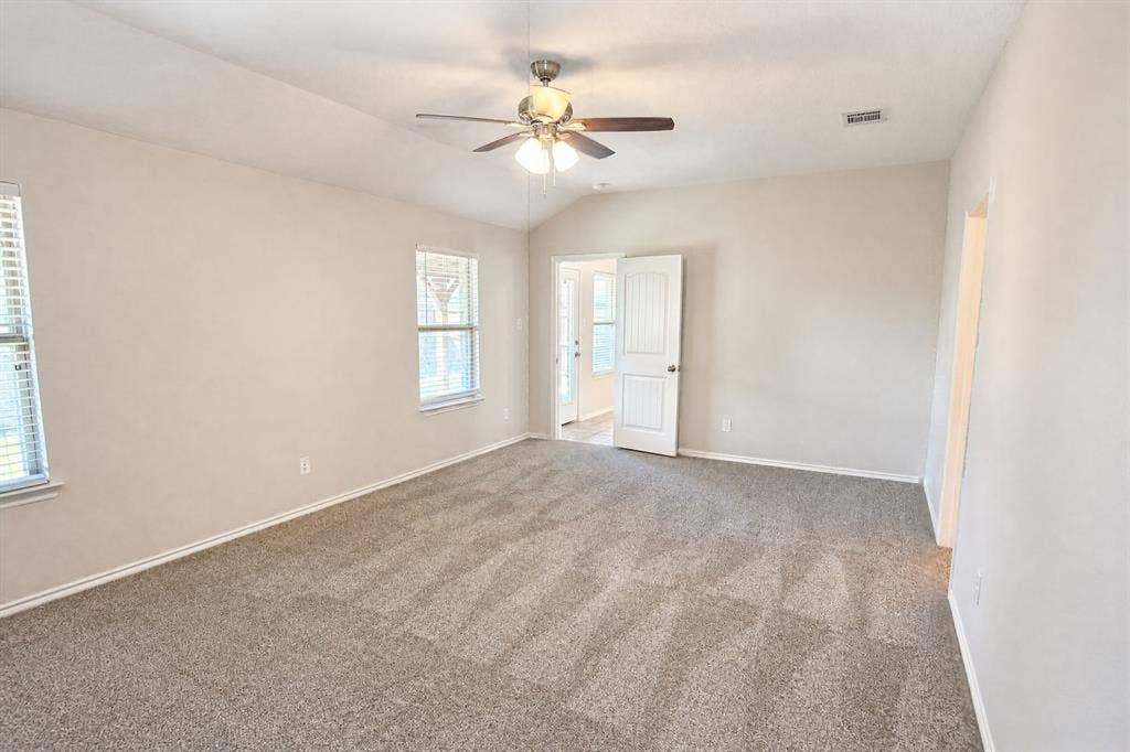 Vaulted ceiling featuring a central multi-light fan, neutral-toned wall-to-wall carpeting, and white interior doors