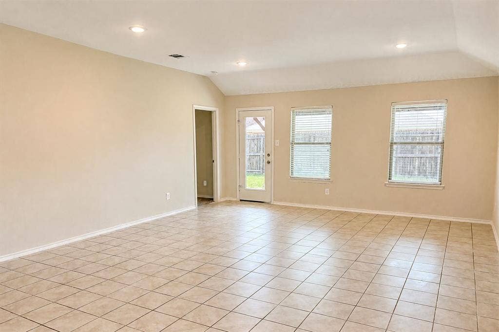 Open-concept space featuring vaulted ceilings, recessed lighting, tile flooring, and multiple windows providing natural light