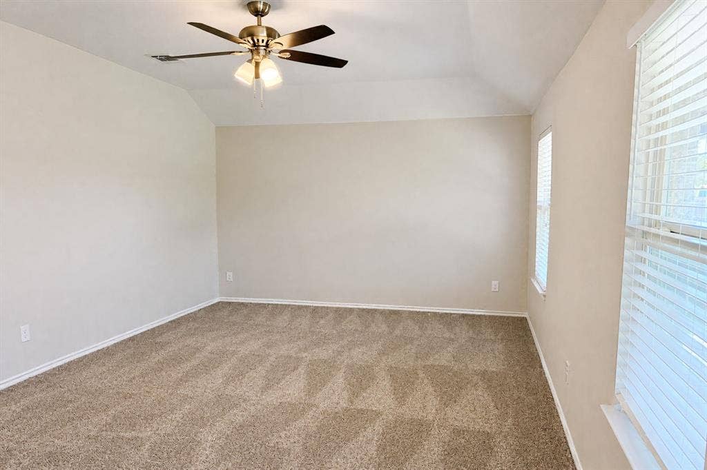 Tray ceiling with a neutral paint palette, plush wall-to-wall carpeting, and a multi-blade ceiling fan with integrated lighting