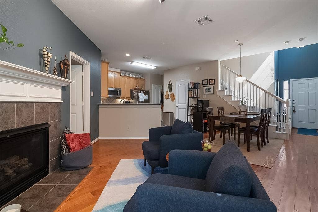 Fireplace with tile surround and mantel, wood-finish flooring, recessed lighting, and open-railing staircase