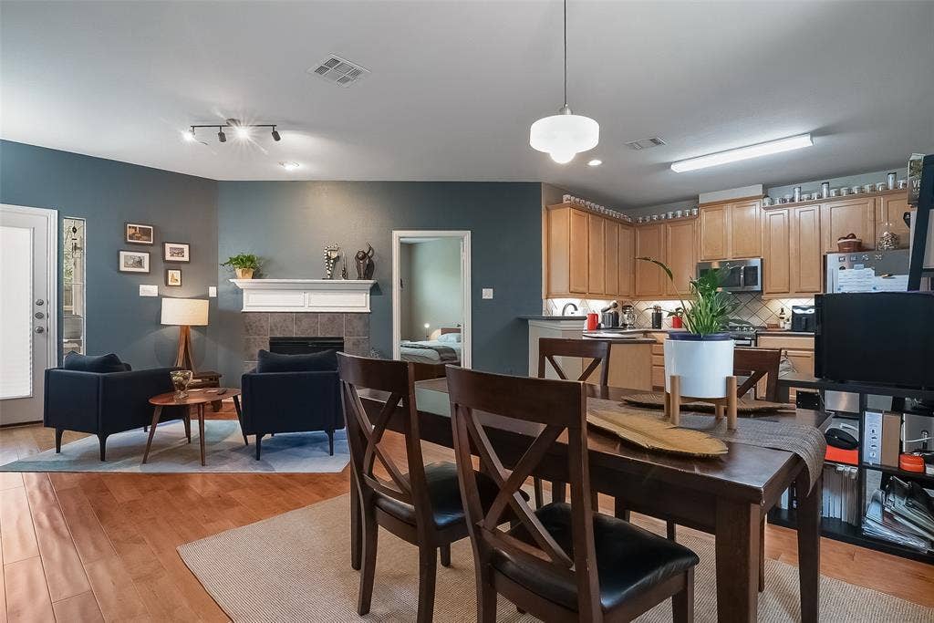 Open-concept interior featuring wood-finish flooring, a fireplace with a mantel, built-in wooden cabinetry, a pendant light fixture, and track lighting