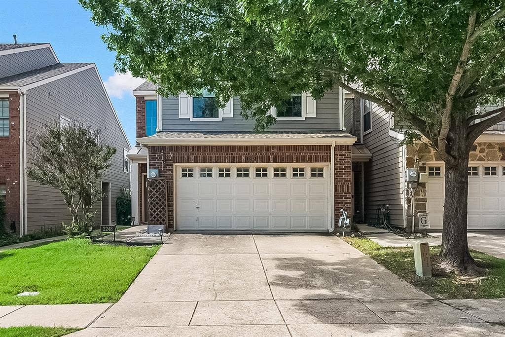 Two-story exterior featuring a brick and horizontal siding facade, a two-car garage with a sectional door, and a paved concrete driveway