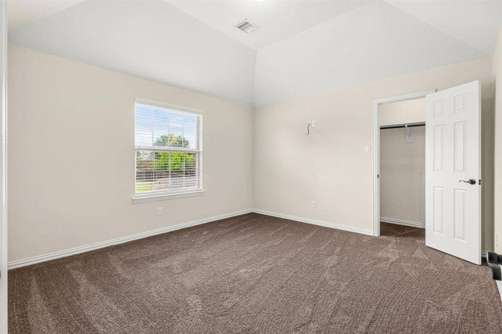 206 White Rock Court, Ovilla, TX 75154 Vaulted ceiling room featuring neutral wall tones, wall-to-wall carpeting, a single-hung window with integrated blinds, and an interior door opening to a closet