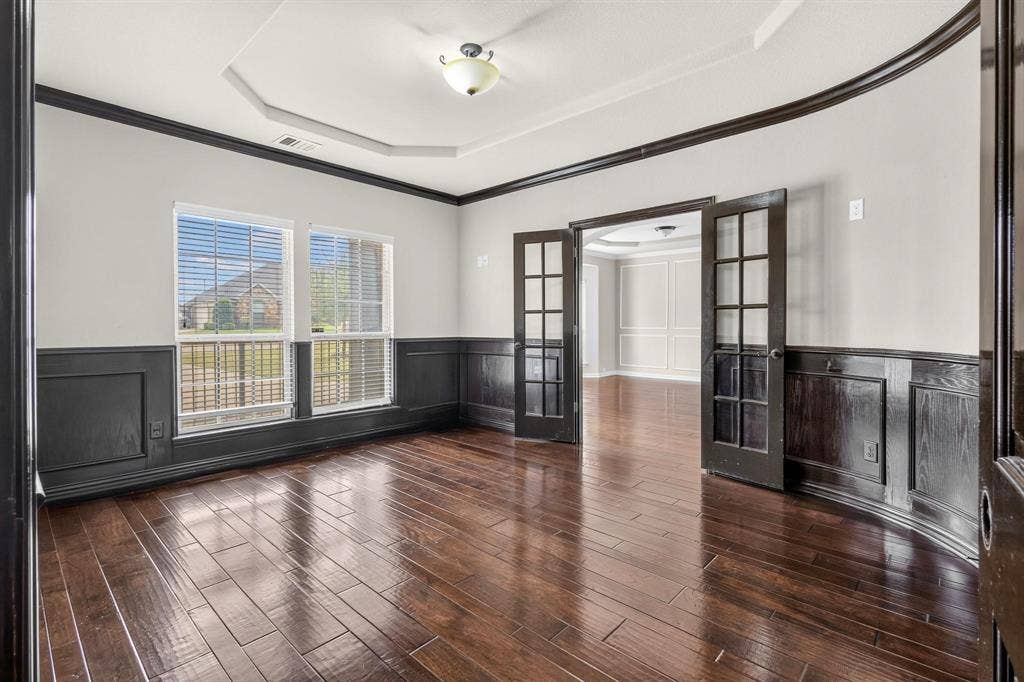 206 White Rock Court, Ovilla, TX 75154 Tray ceiling, dark-stained wood-finish flooring, half-wall wainscoting, and glass-paneled French doors