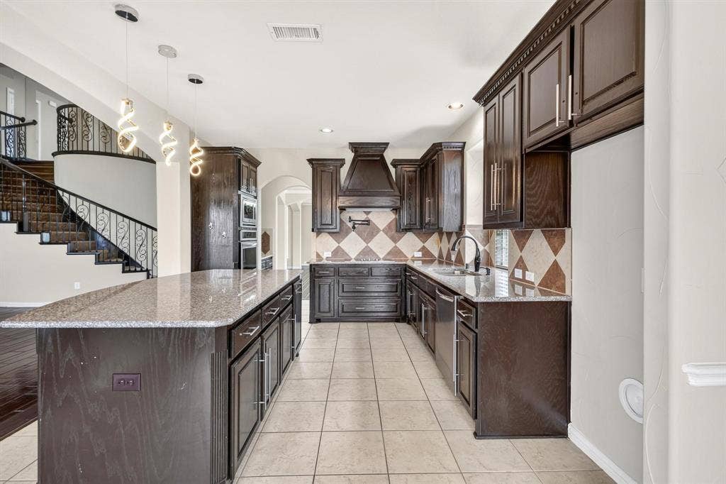 206 White Rock Court, Ovilla, TX 75154 Kitchen featuring dark wood cabinetry, expansive stone-surface island, diamond-pattern tile backsplash, professional-style range hood, and pendant lighting