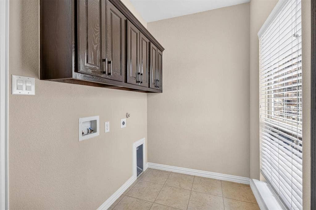 206 White Rock Court, Ovilla, TX 75154 Utility area featuring dark wood-finish cabinetry, neutral tile flooring, and horizontal window blinds