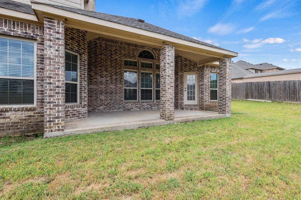 206 White Rock Court, Ovilla, TX 75154 Covered concrete patio featuring brick exterior columns, arched window detailing, and an expansive lawn