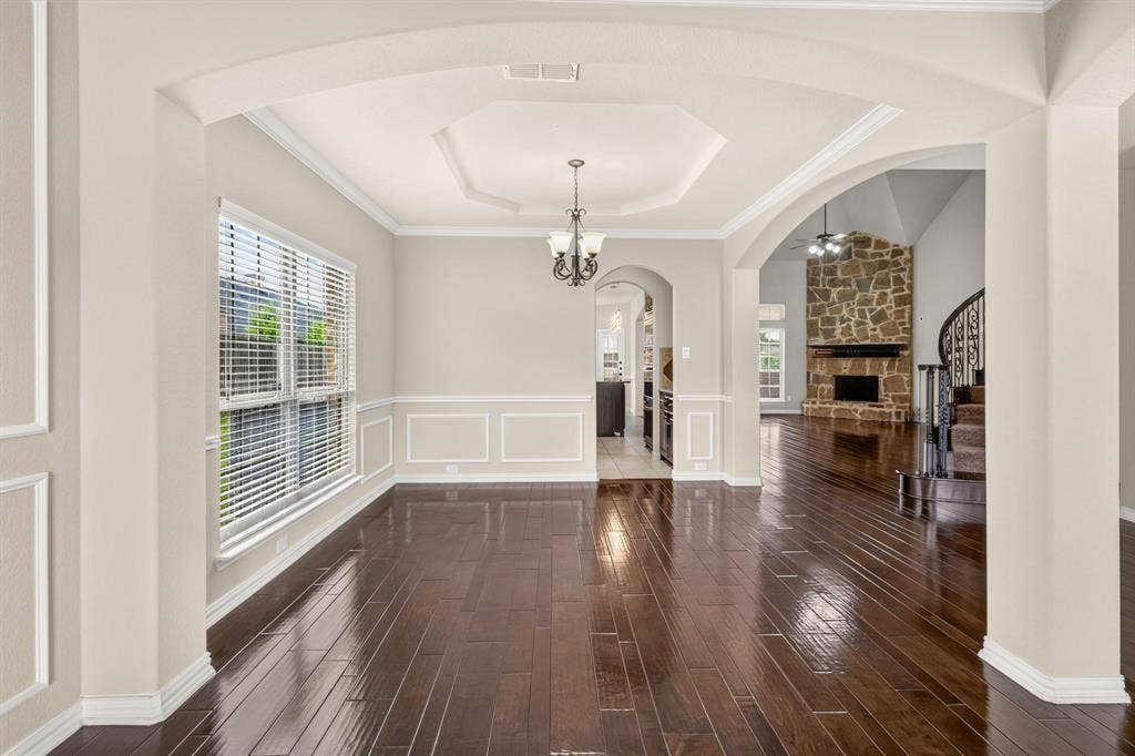206 White Rock Court, Ovilla, TX 75154 Wood-finish flooring, tray ceiling with recessed lighting, crown molding, wainscoting, and stone-surround fireplace