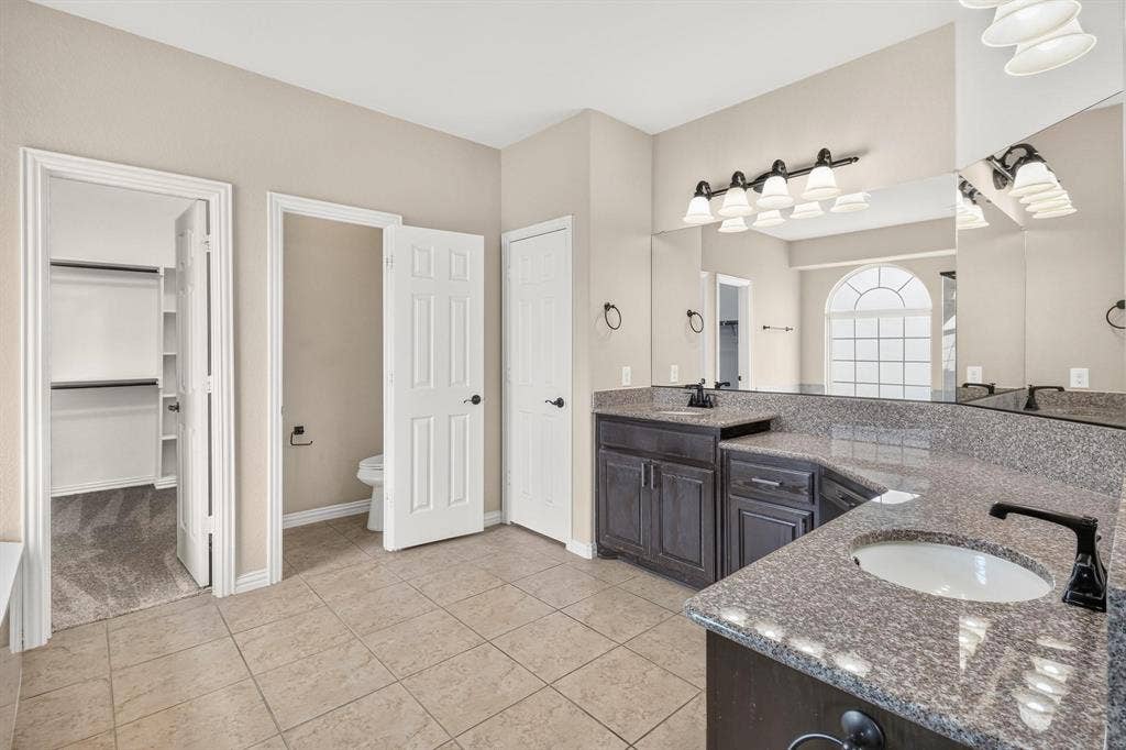 206 White Rock Court, Ovilla, TX 75154 Bathroom featuring dark-finish cabinetry, stone-surface countertops, dual undermount sinks with matte black faucets, and ceramic tile flooring