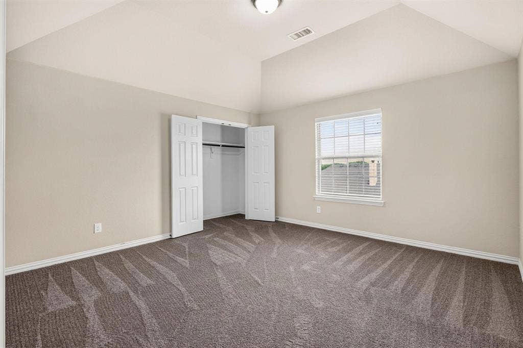 206 White Rock Court, Ovilla, TX 75154 Vaulted ceiling, neutral wall tones, wall-to-wall carpeting, window with muntins, and reach-in closet with double-panel doors