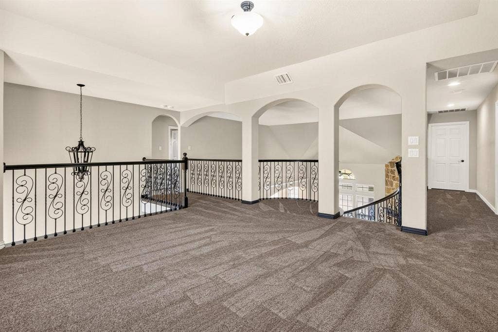 206 White Rock Court, Ovilla, TX 75154 Open landing featuring decorative metal scrollwork railings, arched architectural detailing, wall-to-wall carpeting, and hanging pendant lighting