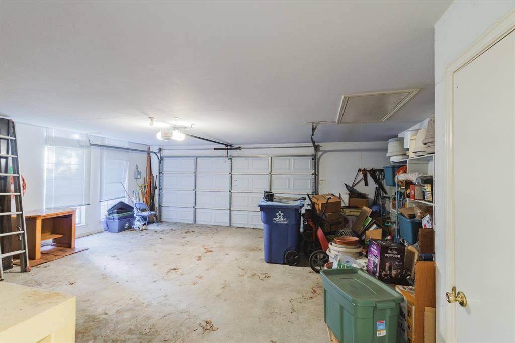 Multi-car garage featuring a sectional overhead door, high ceilings, concrete flooring, and windows for natural light