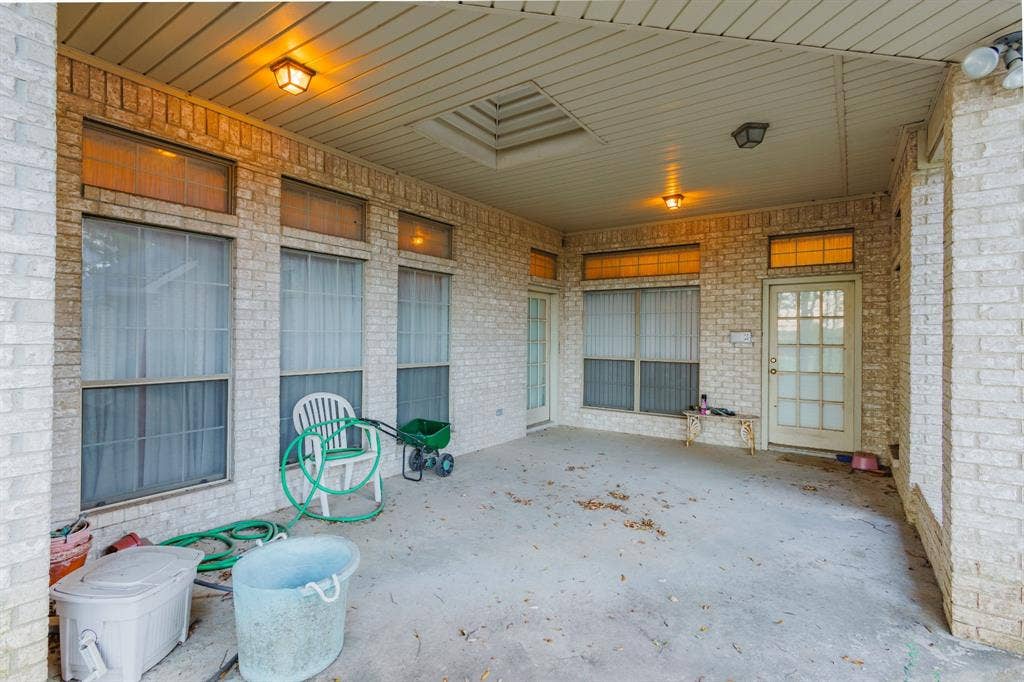 Covered patio featuring brick masonry walls, a recessed skylight, multiple flush-mount light fixtures, and transom windows above the doors and windows