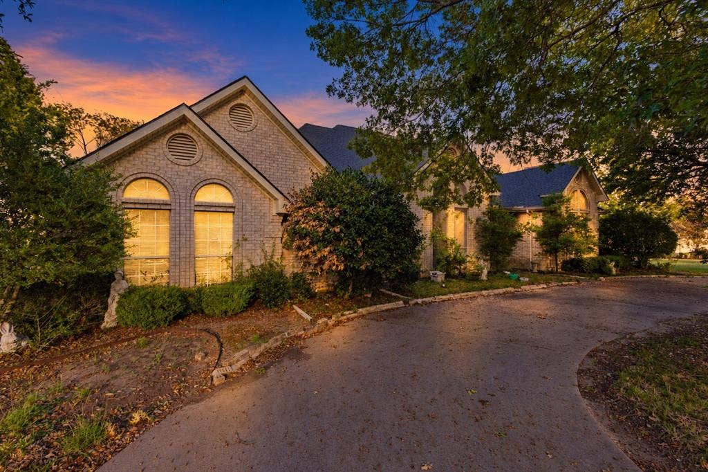 Brick exterior with a gabled roofline, arched windows, and a curved concrete driveway