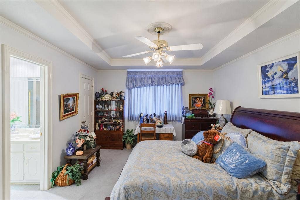 Tray ceiling with a central multi-light ceiling fan and crown molding