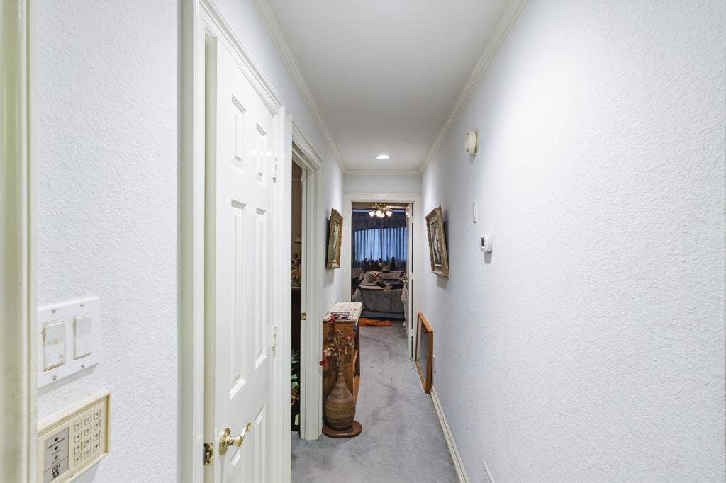 Hallway featuring crown molding, recessed lighting, and solid-core six-panel interior doors with brass-finish hardware