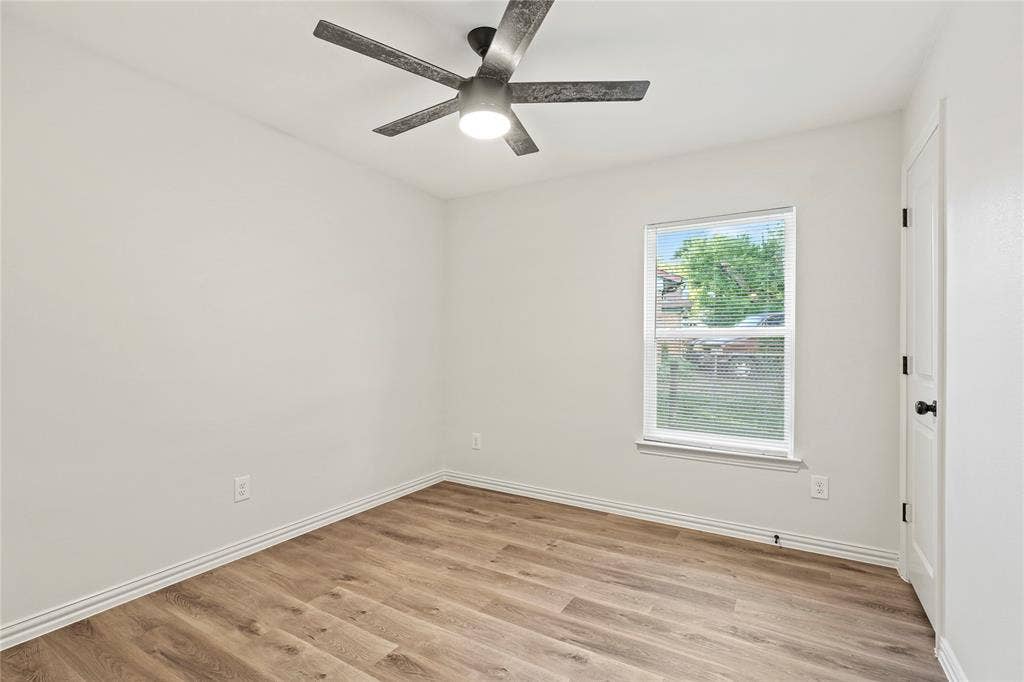 Unfurnished room with light wood finished floors, a ceiling fan, and baseboards
