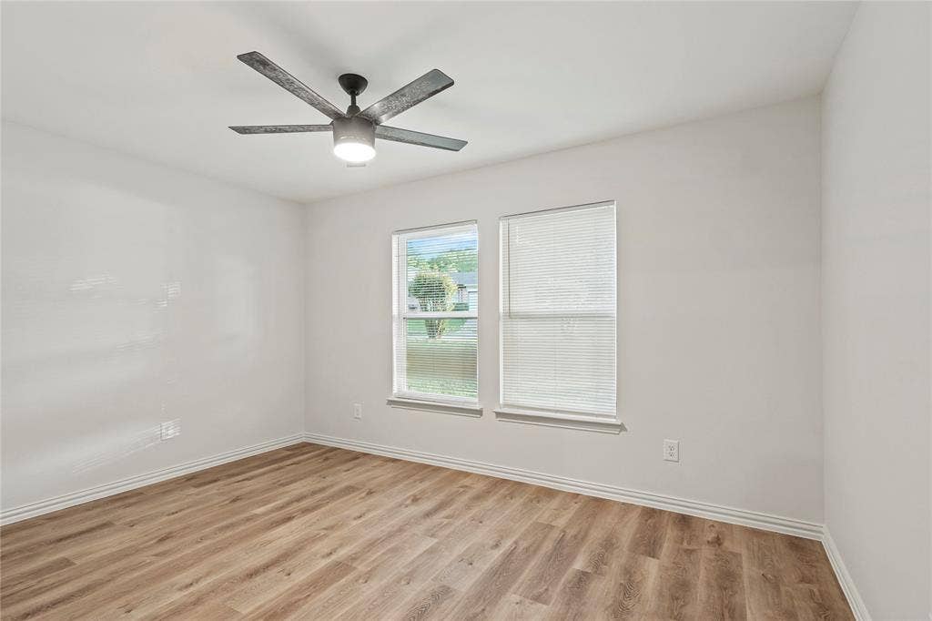 Empty room featuring light wood finished floors, baseboards, and a ceiling fan