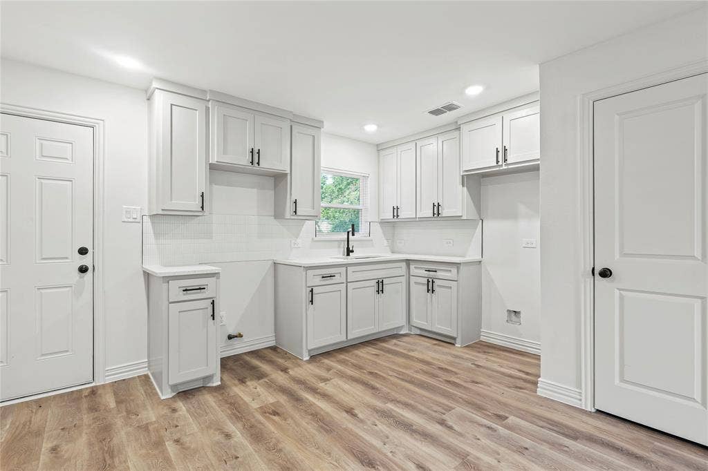 Kitchen featuring a sink, light wood finished floors, backsplash, recessed lighting, and baseboards