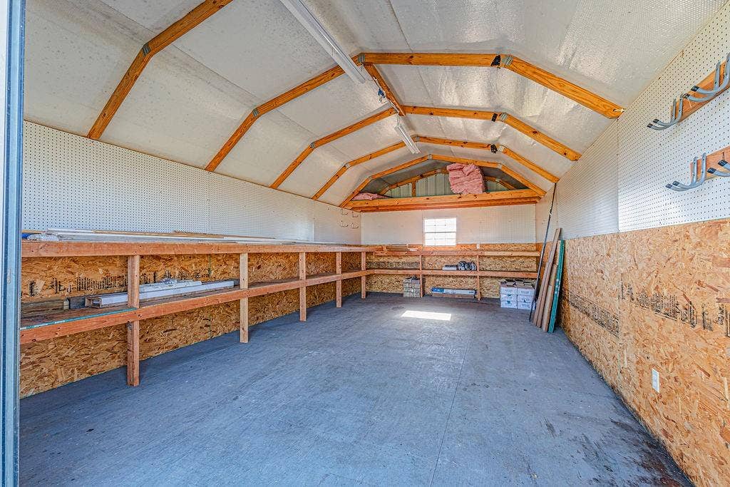 1158 County Road 141, Kaufman, TX 75142 Storage structure with exposed wood framing, built-in wooden shelving, pegboard wall panels, and interior task lighting