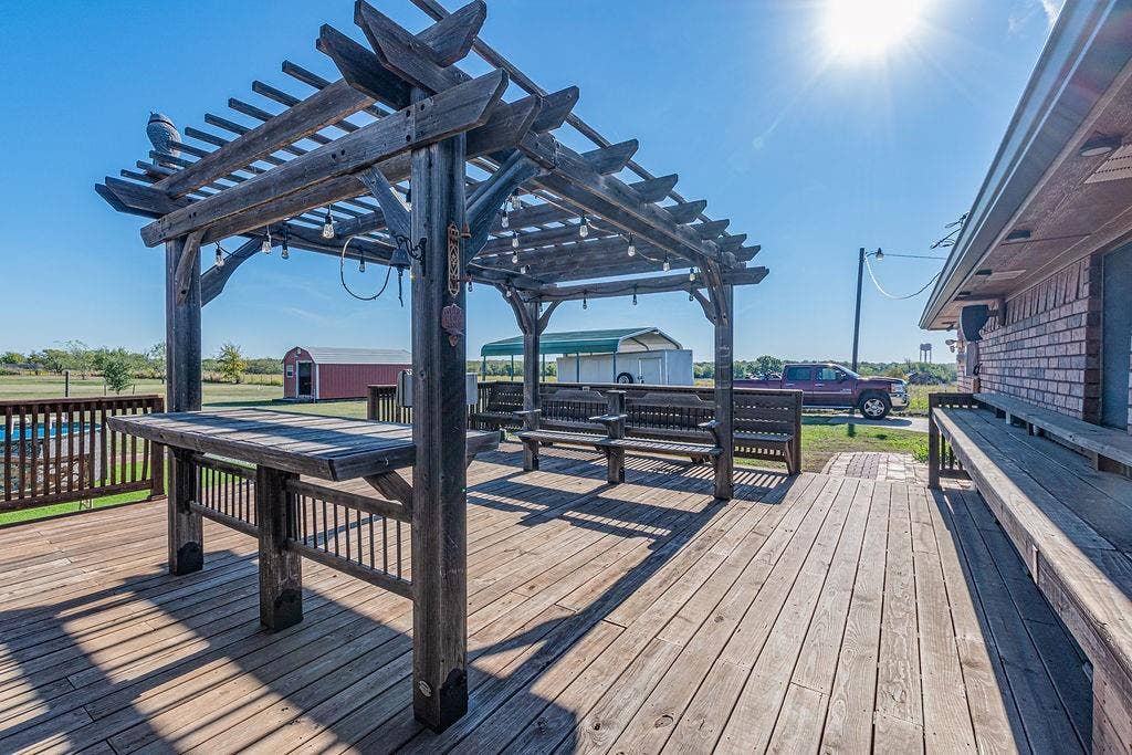 1158 County Road 141, Kaufman, TX 75142 Expansive wood-plank deck featuring a built-in pergola and integrated wooden bench seating