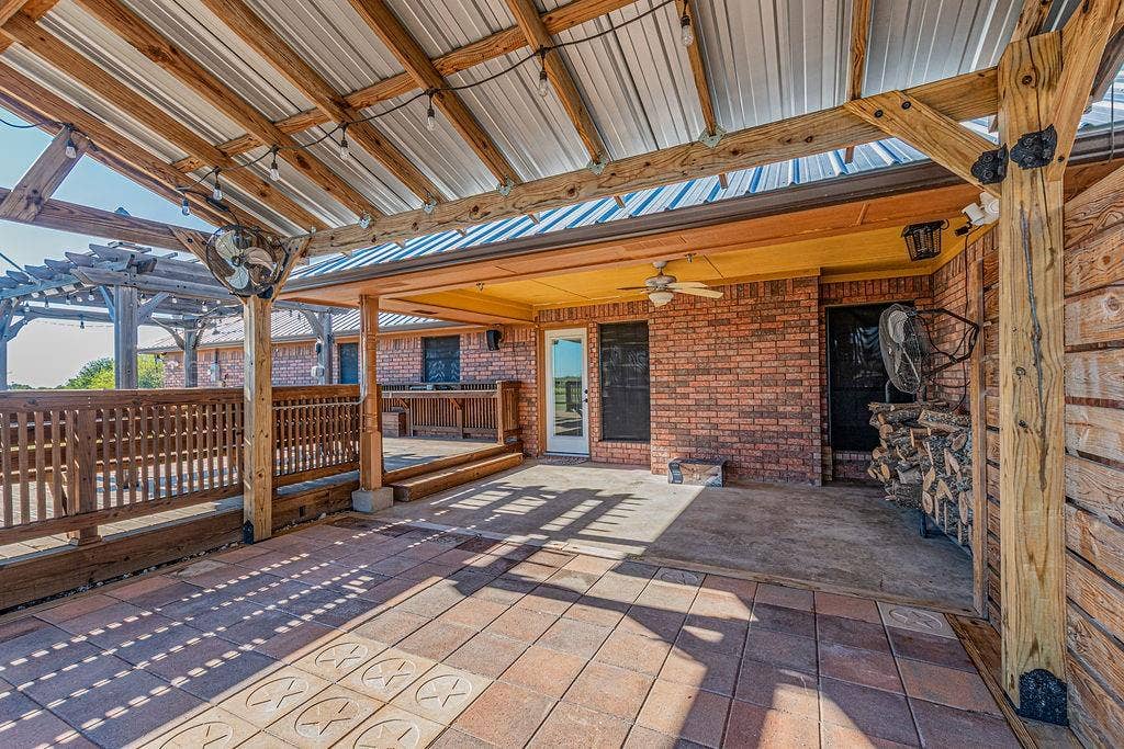 1158 County Road 141, Kaufman, TX 75142 Covered patio featuring a metal roof, wood-frame pergola, patterned concrete pavers, and built-in bar counter