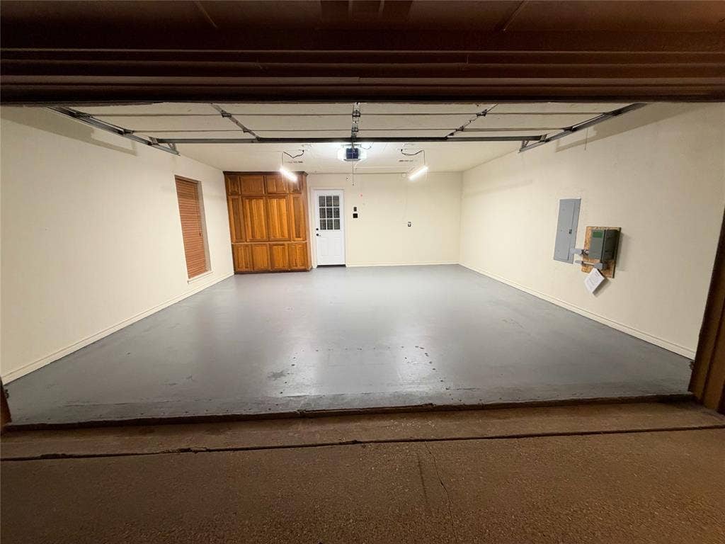 1158 County Road 141, Kaufman, TX 75142 Attached garage featuring a smooth-finished floor, built-in wooden cabinetry, a white panel door with glass inset, and overhead lighting