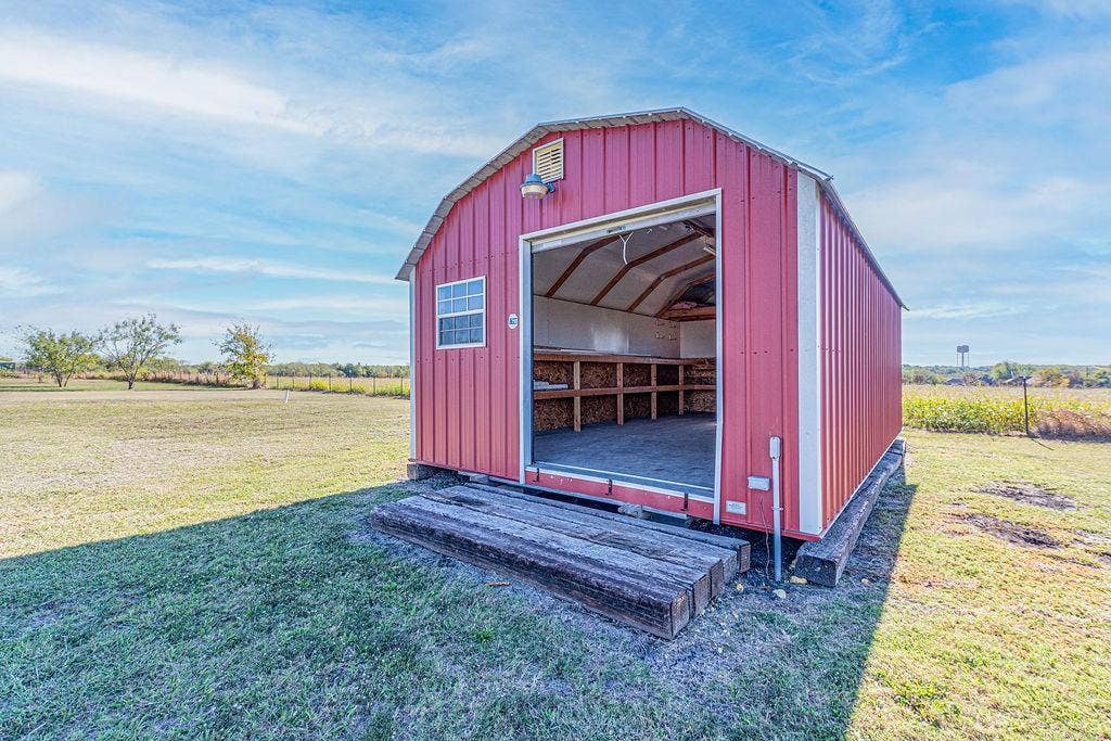 1158 County Road 141, Kaufman, TX 75142 Barn-style exterior outbuilding featuring metal siding, a wide-opening entrance, built-in wooden shelving, and timber-frame foundation supports