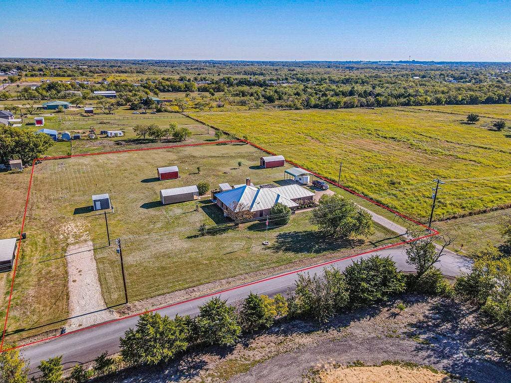 1158 County Road 141, Kaufman, TX 75142 Expansive acreage featuring a detached metal structure, multiple outbuildings, a gravel driveway, and a residential building with a metal roof