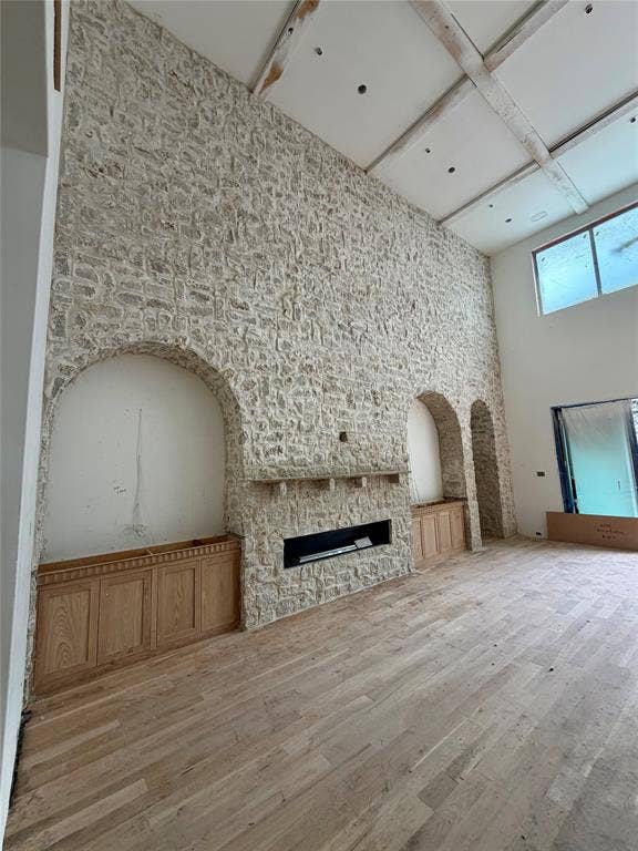 Farched recessed niches, integrated wooden cabinetry, built-in horizontal fireplace, and wood-finish flooring and beams