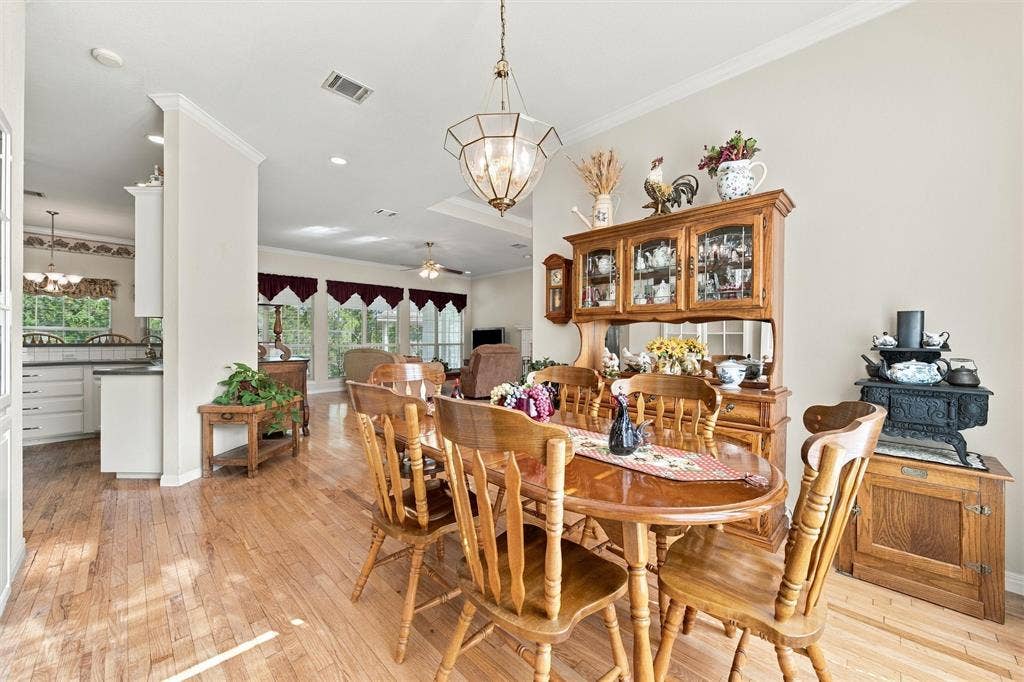5030 Bosque Ridge Road, Crawford, TX 76638 Dining space featuring wood-finish flooring, crown molding, and a geometric multi-light pendant fixture