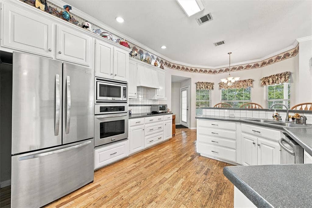 5030 Bosque Ridge Road, Crawford, TX 76638 Kitchen featuring white cabinetry, wood-finish flooring, stainless steel appliances, a built-in wall oven and microwave, and recessed lighting