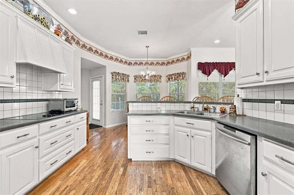5030 Bosque Ridge Road, Crawford, TX 76638 Kitchen featuring white shaker-style cabinetry, dark solid-surface countertops, square tile backsplash with decorative accents, wood-finish flooring, and recessed lighting