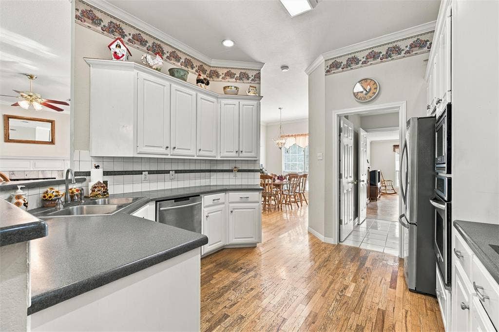 5030 Bosque Ridge Road, Crawford, TX 76638 Kitchen featuring white cabinetry, solid-surface countertops, tile backsplash, wood-finish flooring, and built-in stainless steel double wall ovens