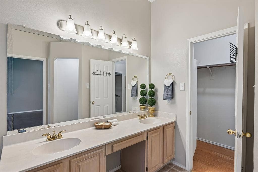 3837 Pine Valley Drive, Plano, TX 75025 Double vanity with integrated sinks, neutral solid-surface countertop, six-light fixture, and built-in cabinetry