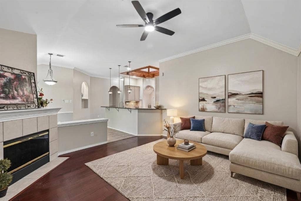 3837 Pine Valley Drive, Plano, TX 75025 Vaulted ceilings with a central ceiling fan, fireplace with tile surround, wood-finish flooring, and arched architectural details