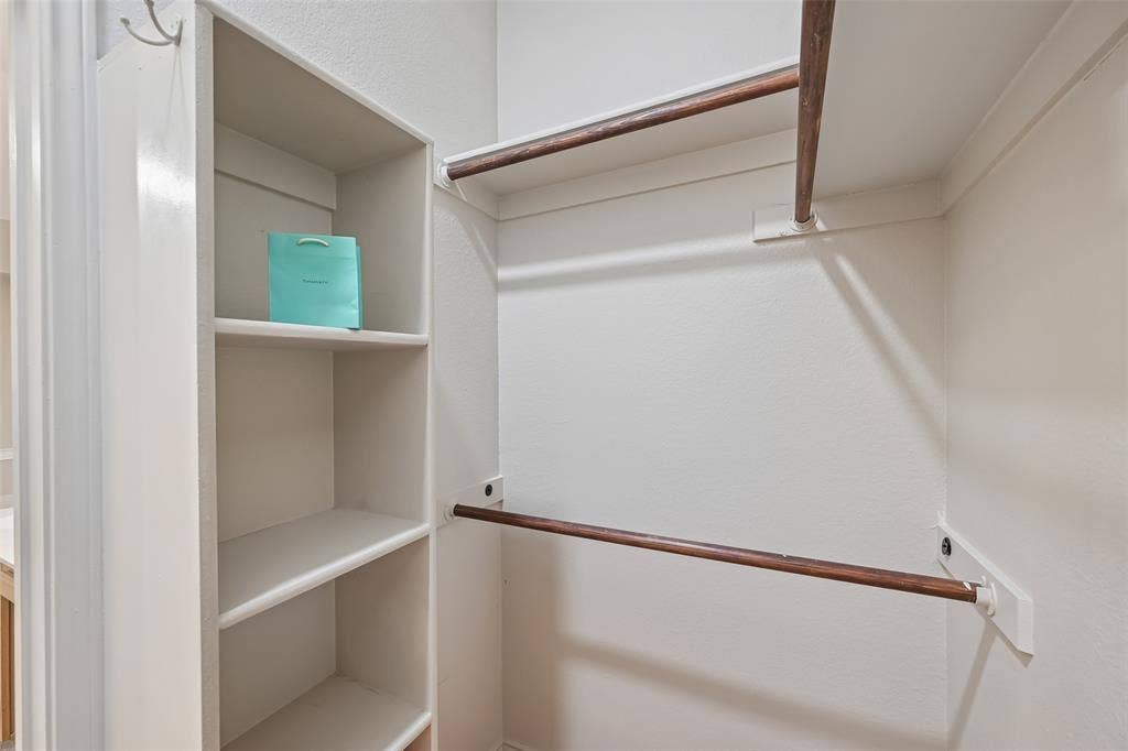 3837 Pine Valley Drive, Plano, TX 75025 Storage area featuring built-in vertical shelving and dual-tier wooden hanging rods