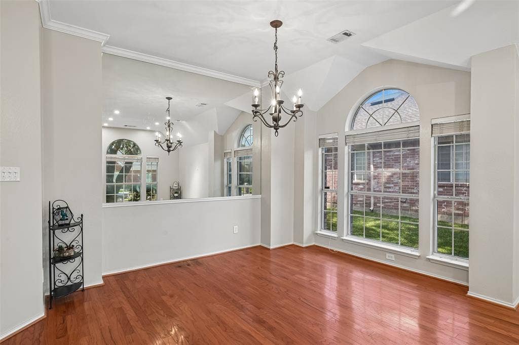 3837 Pine Valley Drive, Plano, TX 75025 Vaulted ceilings with an expansive wall mirror, wood-finish flooring, multi-pane arched windows, and a decorative metal chandelier