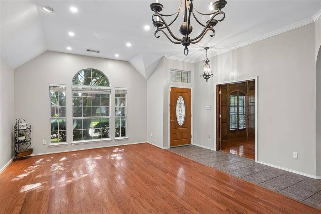 3837 Pine Valley Drive, Plano, TX 75025 Vaulted ceilings featuring recessed lighting, wood-finish flooring, an arched window, a solid wood entry door with an oval glass insert, and a decorative wrought iron chandelier