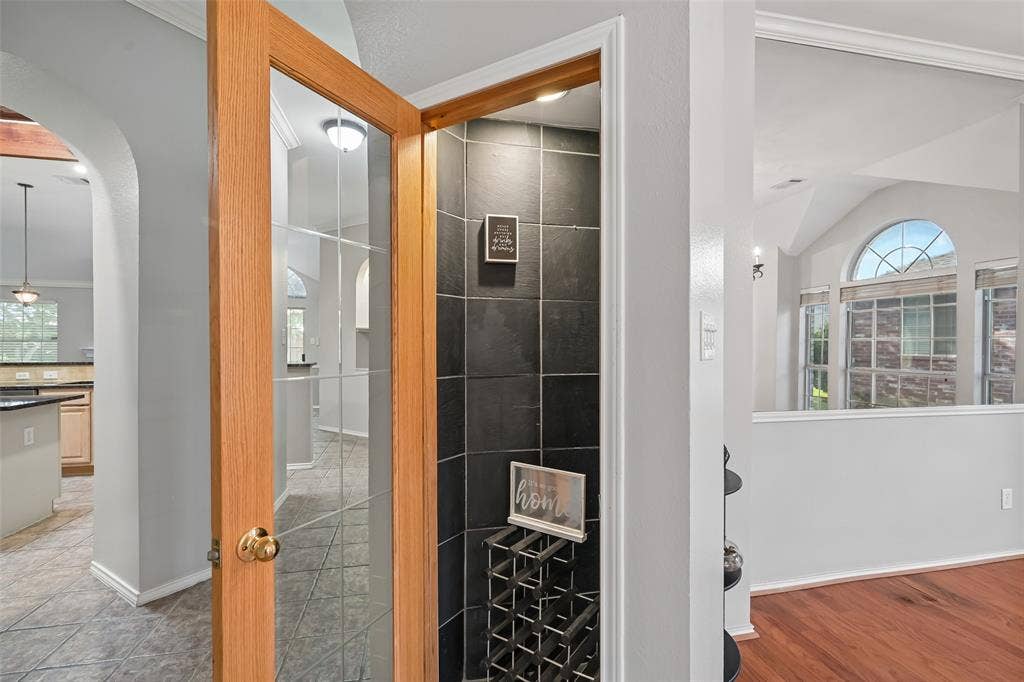 3837 Pine Valley Drive, Plano, TX 75025 Wine closet, glass-paneled wood door entry, dark tile accent wall, and recessed lighting