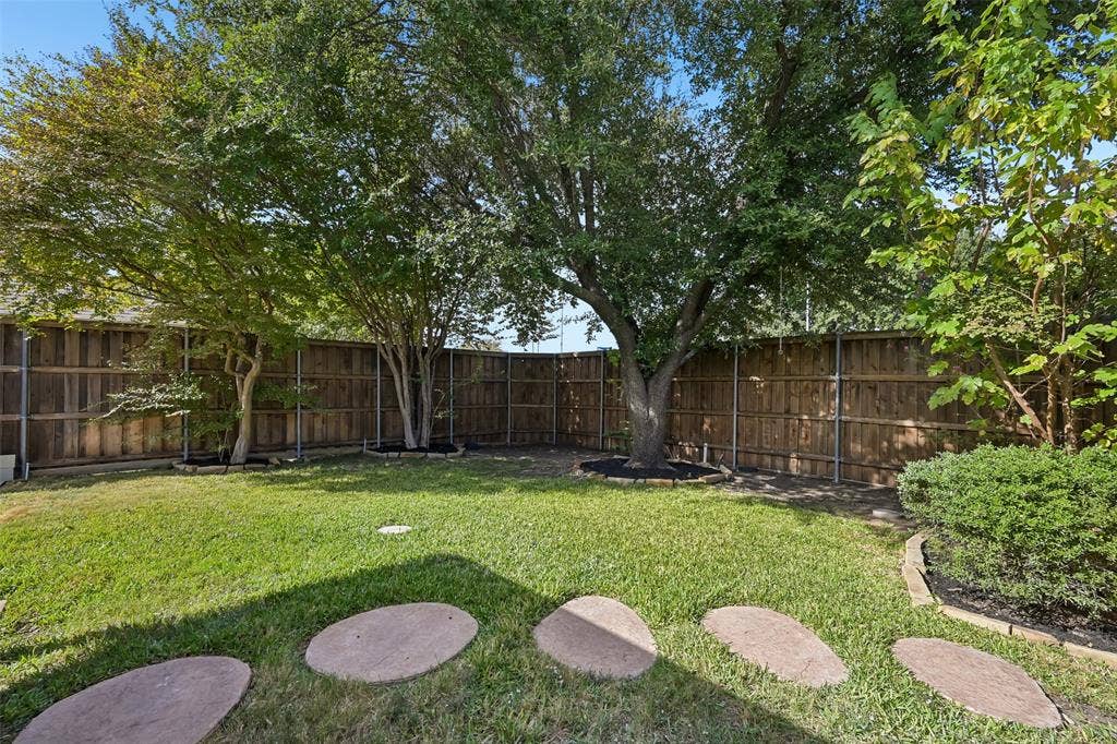 3837 Pine Valley Drive, Plano, TX 75025 Backyard featuring mature trees, wood privacy fencing, a manicured lawn, and stone paver path